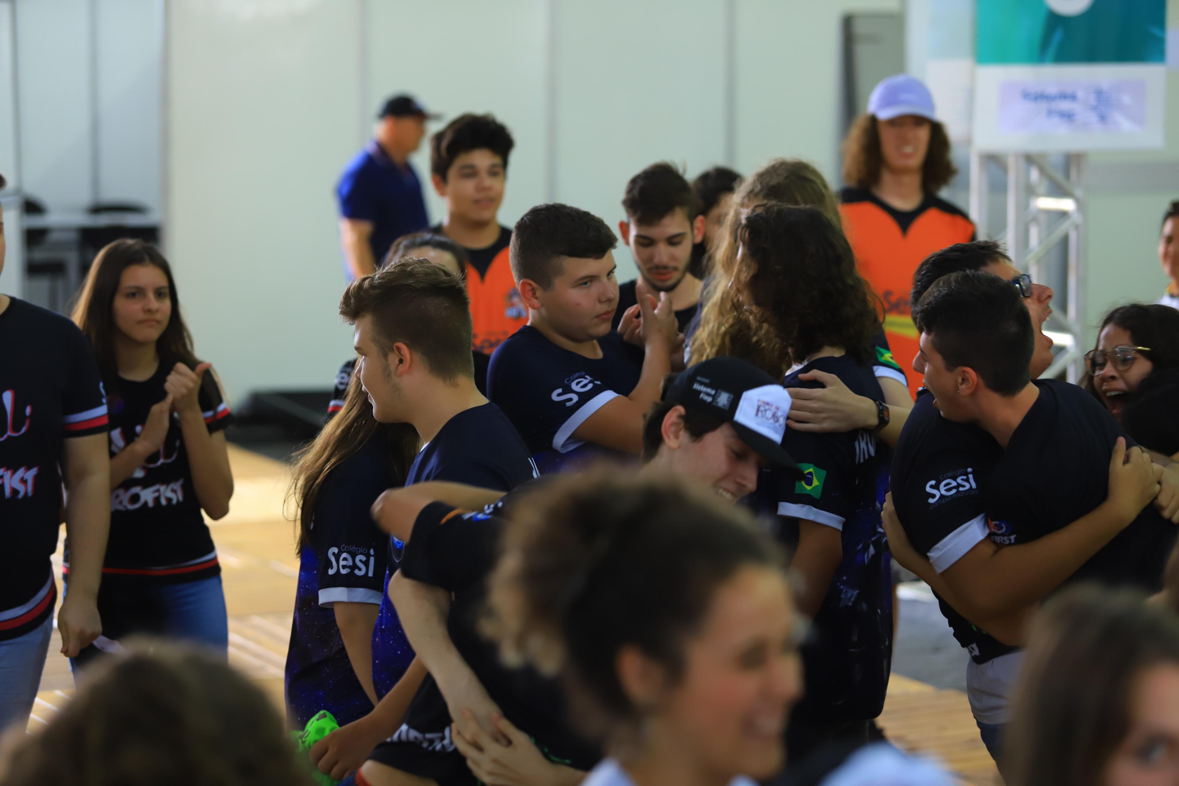 Grupo de estudantes se abraçando no meio da competição